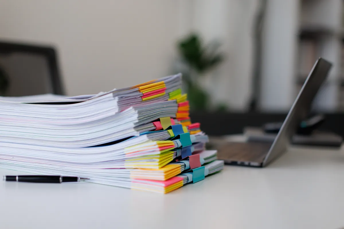 Stacks of tabbed case files beside a laptop on a clean white desk
