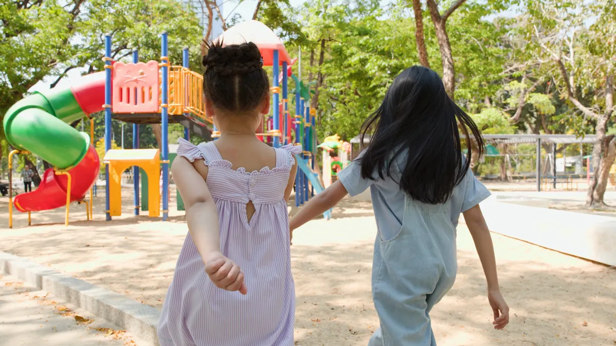 Two young children seen from behind heading to a playground