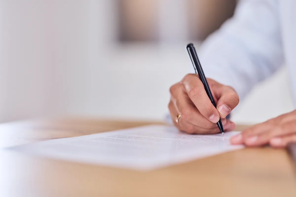 Hand signing a document with a pen