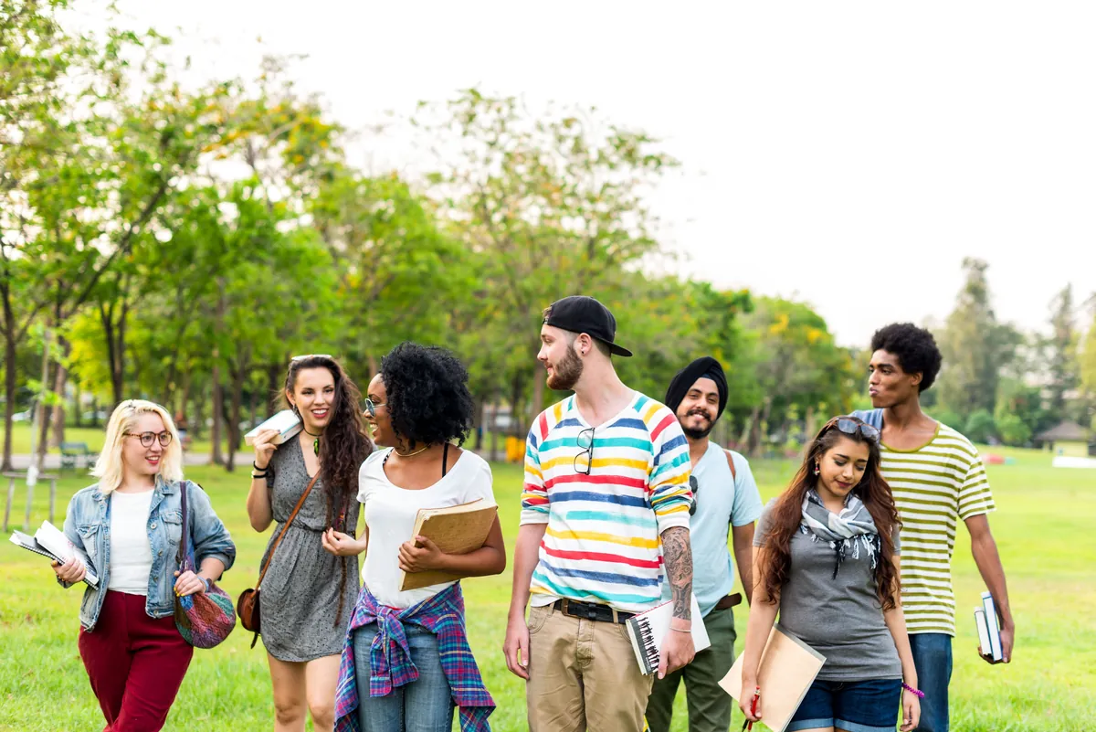 Diverse group of students walking across a sunny university lawn
