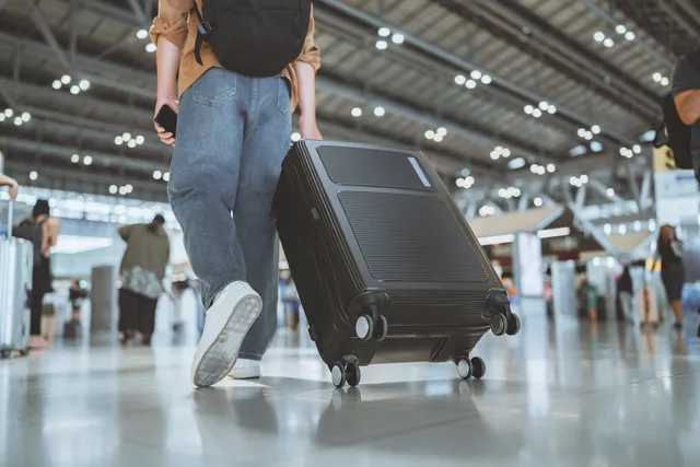 Traveller with a suitcase walking through an airport terminal