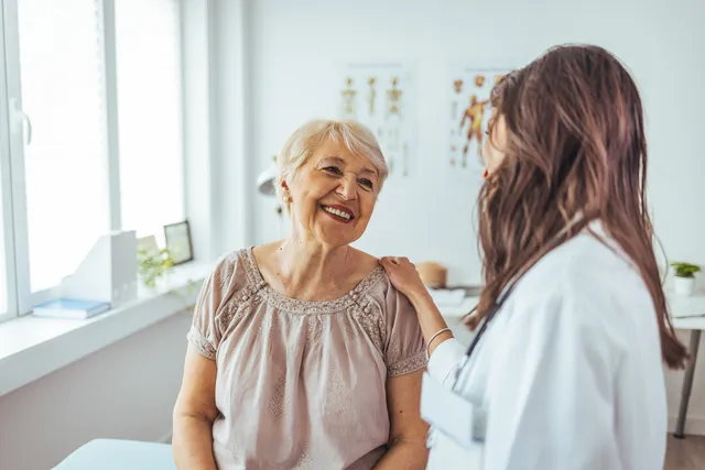 Older patient smiling with a doctor in a bright clinic