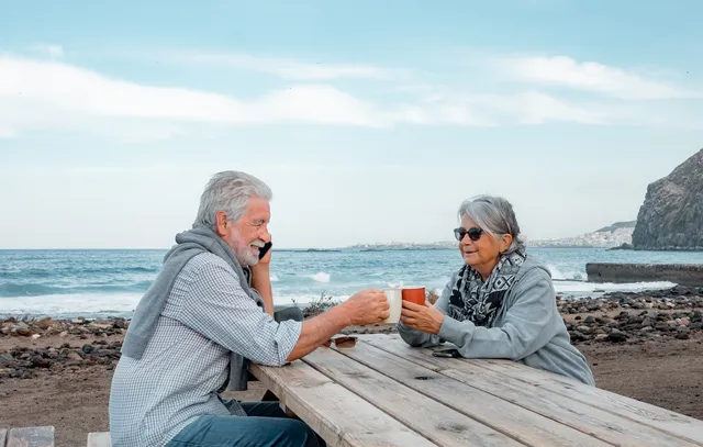 Older couple enjoying coffee at a seaside table