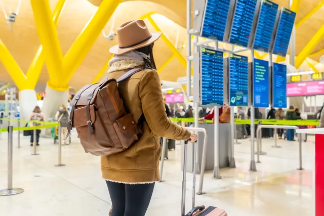 Traveller with luggage looking at airport departure boards